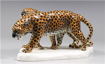 A glossy ceramic sculpture of two leopards in a dynamic pose.