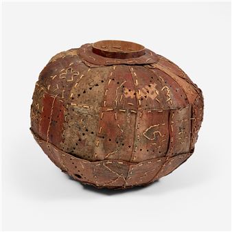 A spherical wooden sculpture with stitched seams and decorative markings.