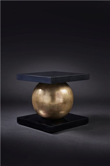 A minimalist sculpture featuring a golden sphere suspended between two dark square platforms.