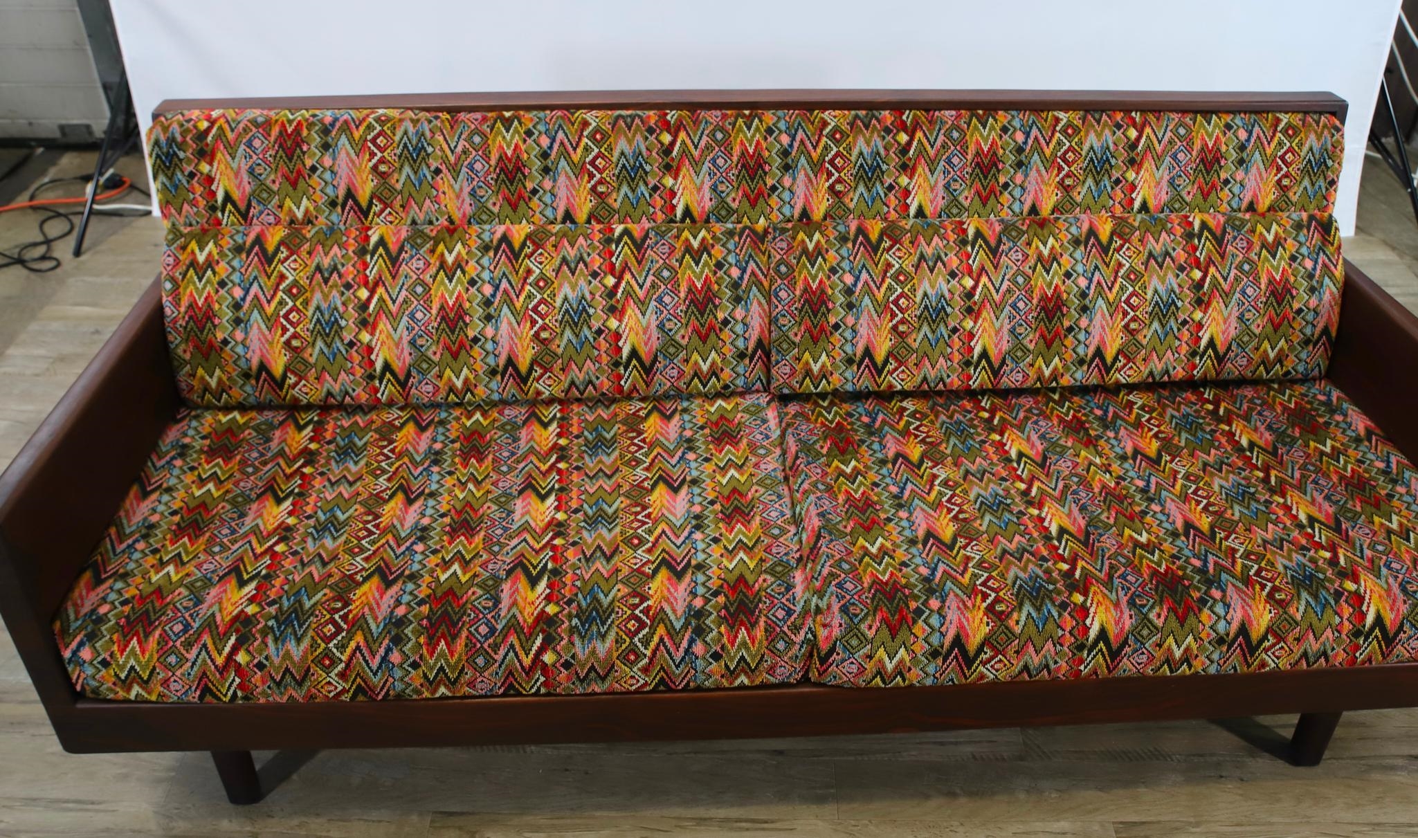 Artwork by Harvey Lowe, Sofa on slightly tapered square legs with multicolored diamond flame upholstered removable seat and back cushions, Made of olive green upholstery