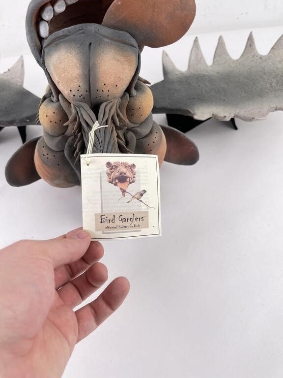 A whimsical moose head sculpture mounted on a wall with exaggerated features and large antlers.