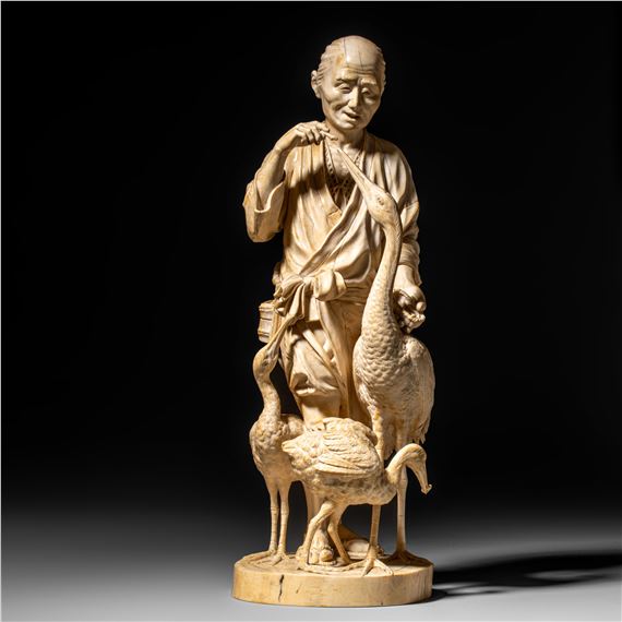 A Japanese Meiji period ivory okimono depicting an old man feeding cranes