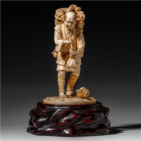 A Japanese ivory okimono of a farmer filling up his pipe