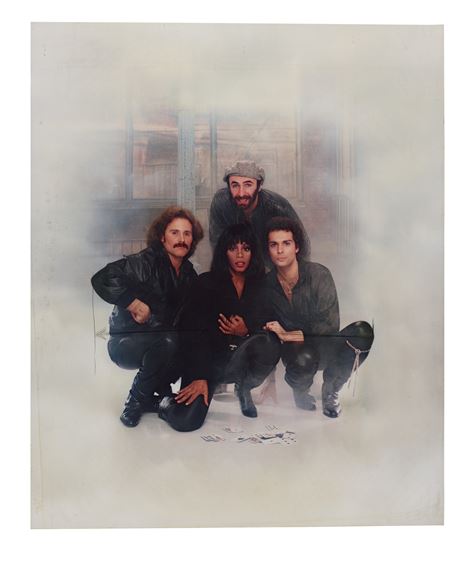 A group of four figures in dark clothing pose together against a misty, atmospheric backdrop.