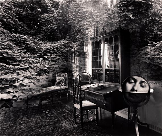 A surreal black-and-white interior scene where a human face is superimposed onto a globe resting on a desk.