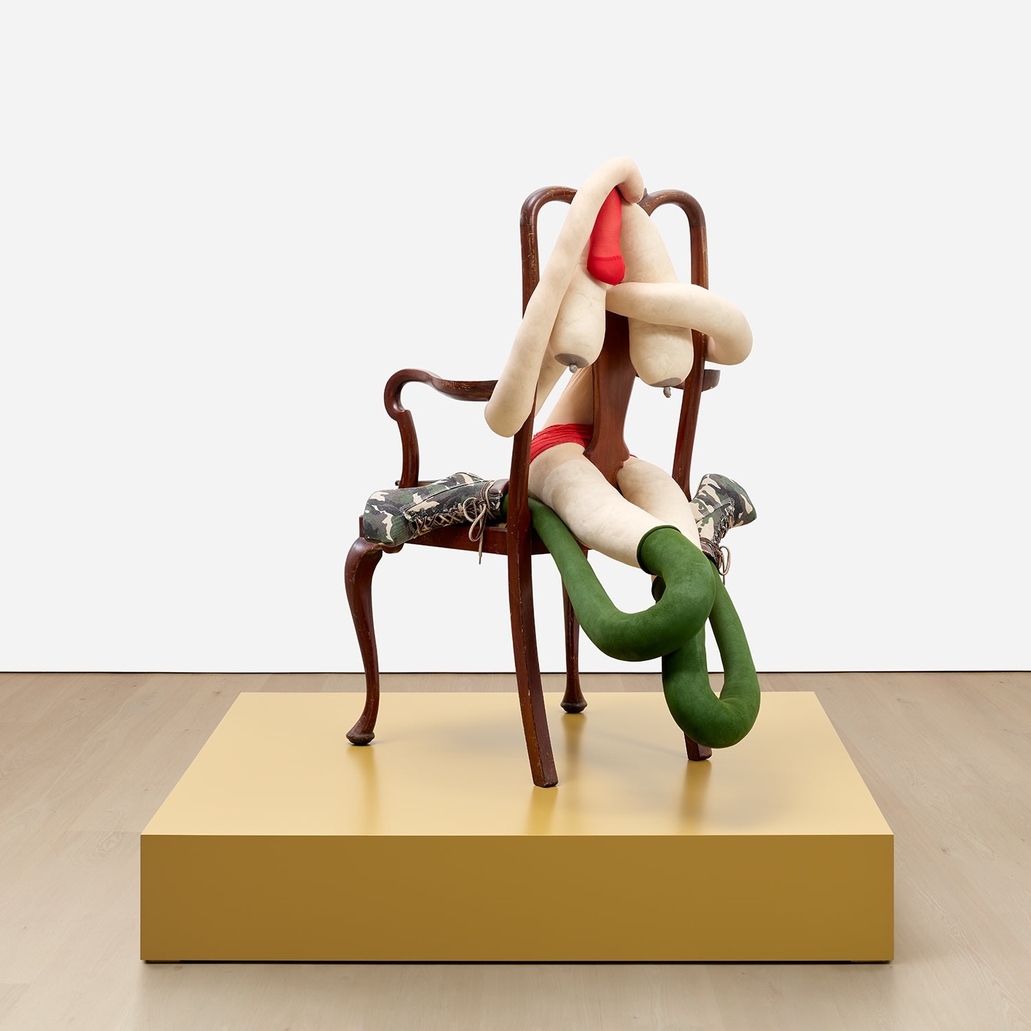 Artwork by Sarah Lucas, SOMEONE DROPPED A BOMB ON ME, Made of tights, wire, wool, bulldog clip, shoes, acrylic, wooden chair, on artist's wooden plinth