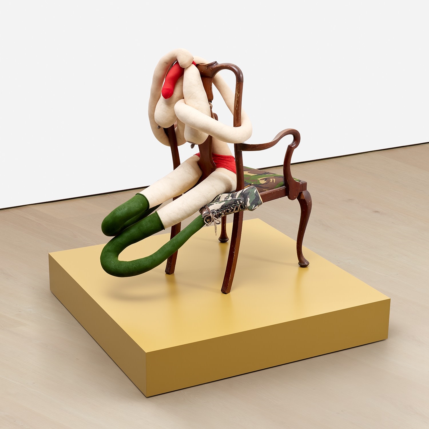 Artwork by Sarah Lucas, SOMEONE DROPPED A BOMB ON ME, Made of tights, wire, wool, bulldog clip, shoes, acrylic, wooden chair, on artist's wooden plinth