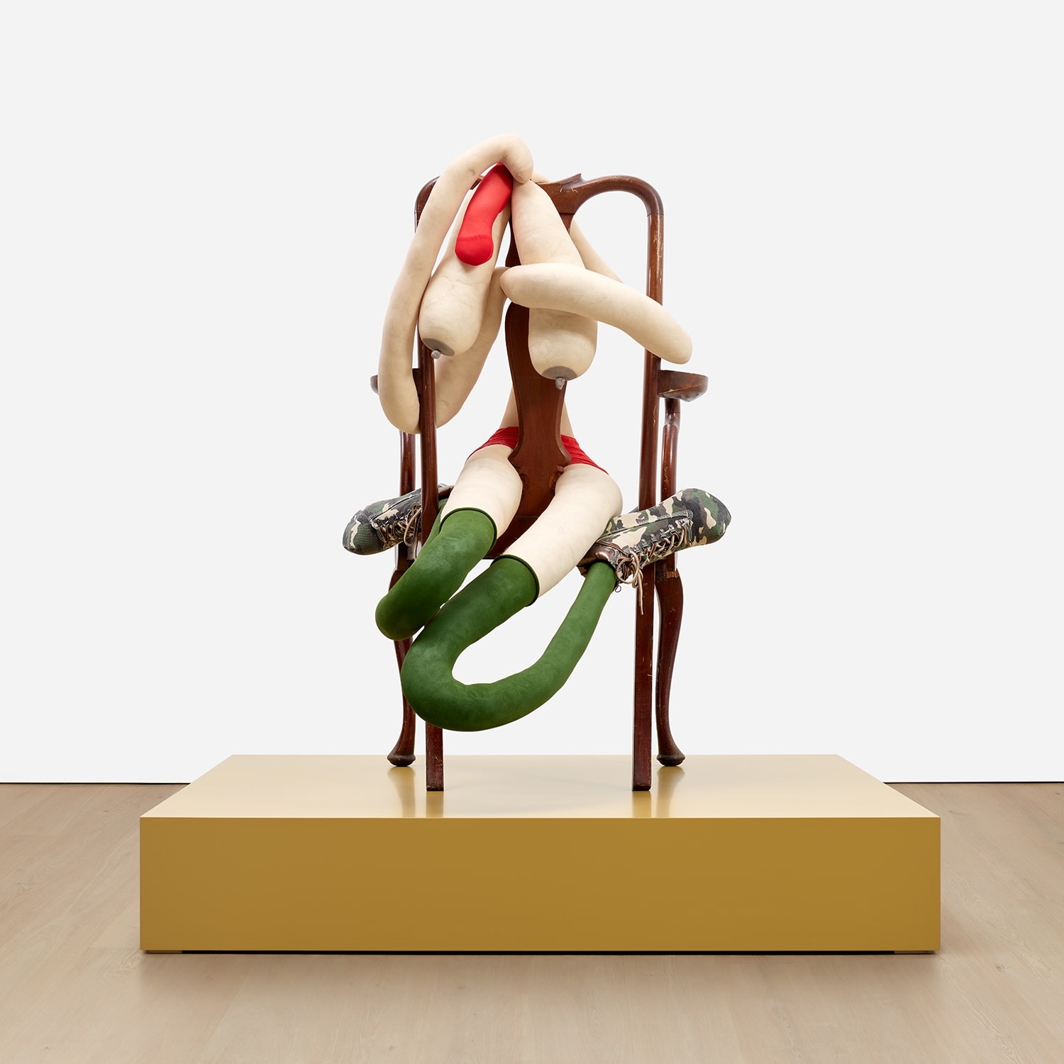 Artwork by Sarah Lucas, SOMEONE DROPPED A BOMB ON ME, Made of tights, wire, wool, bulldog clip, shoes, acrylic, wooden chair, on artist's wooden plinth