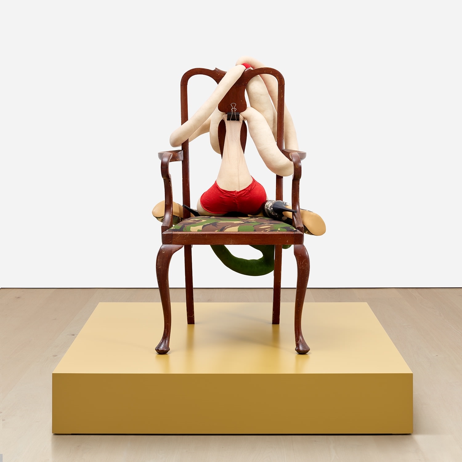 Artwork by Sarah Lucas, SOMEONE DROPPED A BOMB ON ME, Made of tights, wire, wool, bulldog clip, shoes, acrylic, wooden chair, on artist's wooden plinth