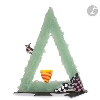 A geometric sculpture featuring a translucent green triangle with colorful patterned accents and a small striped cup inside.