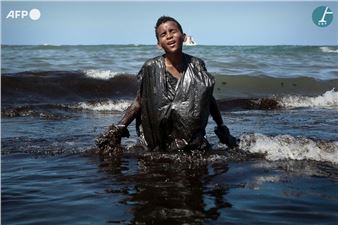 Child coming out of the water during an oil clean-up operation on Itapuama beach - Leo Malafaia