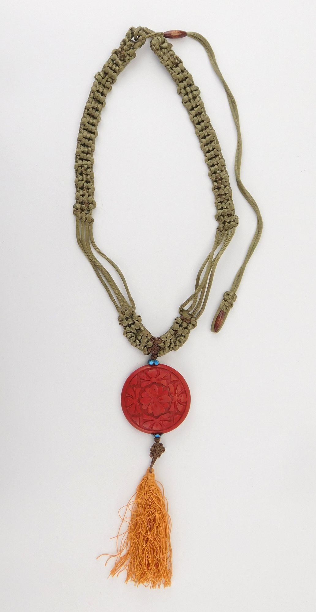 Artwork by Simone Samuels, Macramé and cinnabar necklace- intricately woven necklace with a carved cinnabar round pendant, Made of carved cinnabar