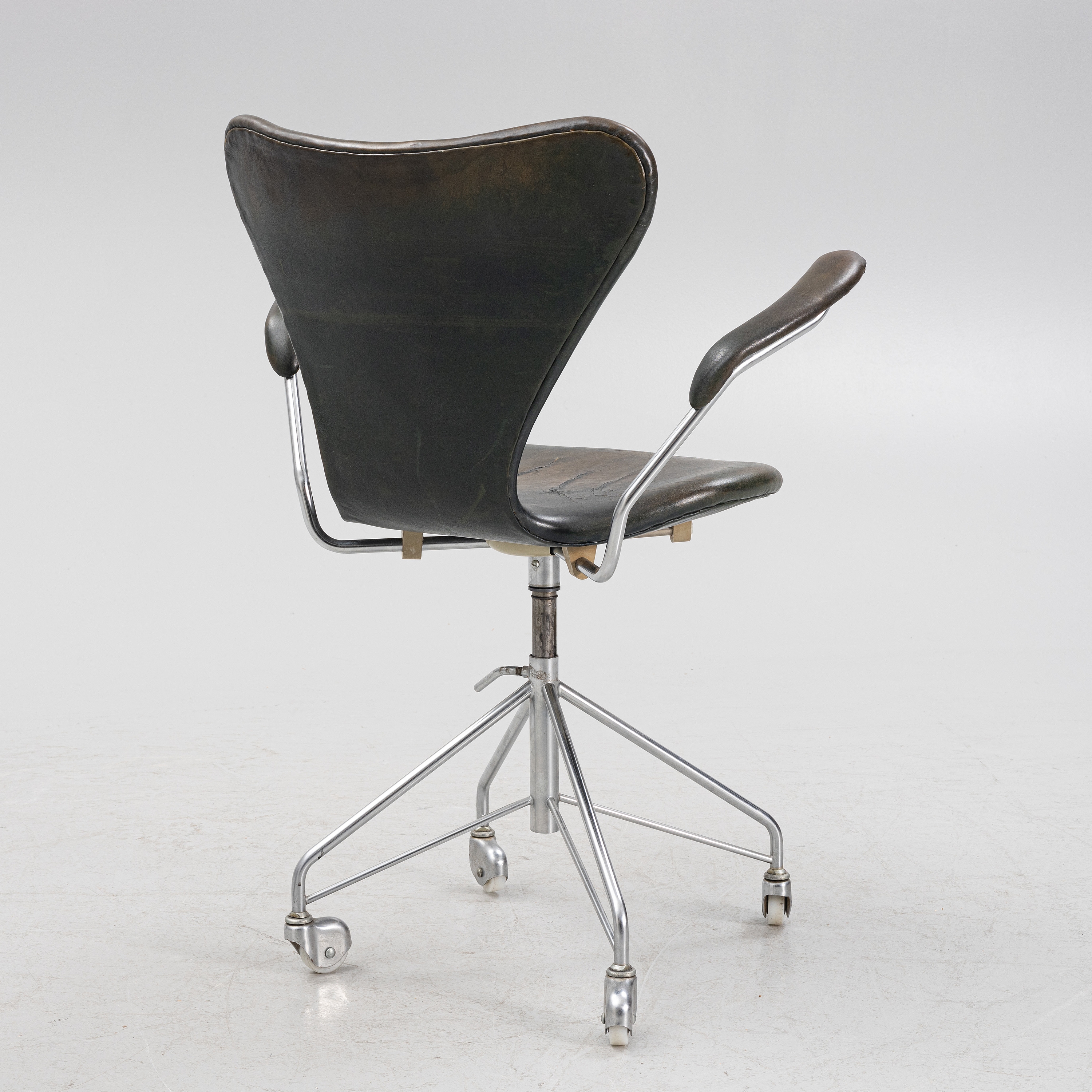 Artwork by Arne Jacobsen, a 'Sjuan' swivel chair, Fritz Hansen, Denmark 1970, Made of Chrome plated metal base on four wheels, upholstered seat and back with dark green/black leather