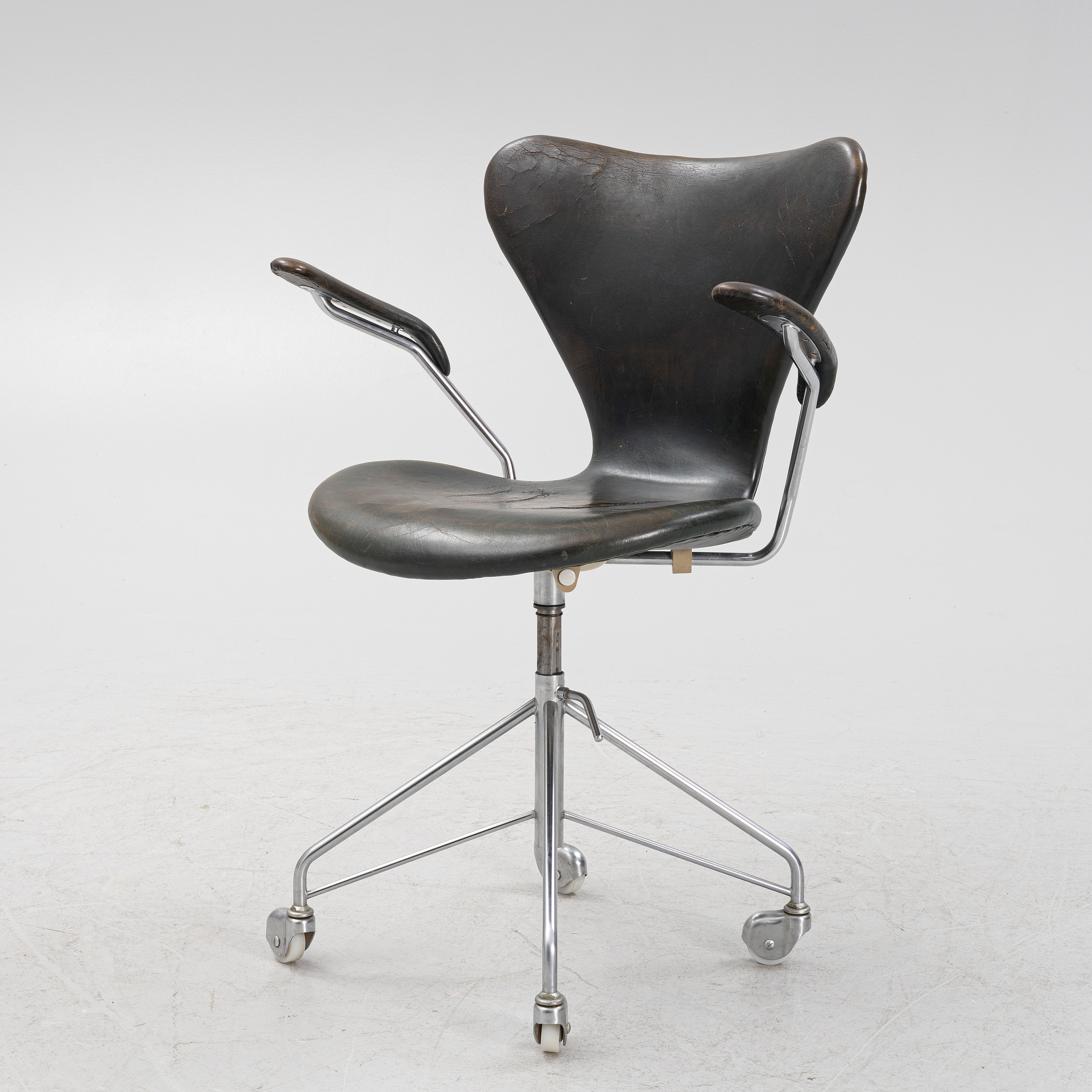 Artwork by Arne Jacobsen, a 'Sjuan' swivel chair, Fritz Hansen, Denmark 1970, Made of Chrome plated metal base on four wheels, upholstered seat and back with dark green/black leather