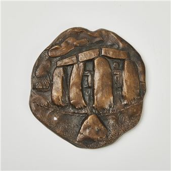 A bronze relief sculpture depicting a prehistoric stone structure with rough, organic edges.