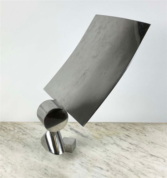 A sleek, curved metallic sculpture resting on a marble surface.