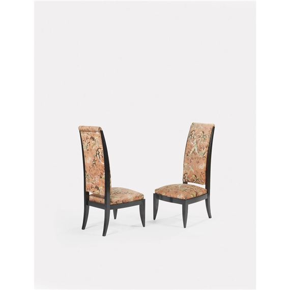 Paire de chauffeuses basses en bois relaqué noir, à haut et étroit dossier légèrement galbé, reposant sur des pieds fuselés ; assise et dossier tendus de toile de coton d'origine, à décor de personnages dans une nature luxuriante, se détachant sur un fond corail. by André Domin, Marcel Genevrière, circa 1930