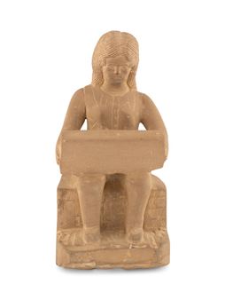 A seated figure in a stone-like material, depicted reading at a desk.