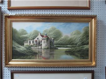 A framed landscape painting of a stone castle by a river surrounded by lush green trees.