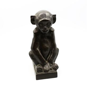 A dark bronze sculpture of a seated monkey figure with a smooth, reflective surface.