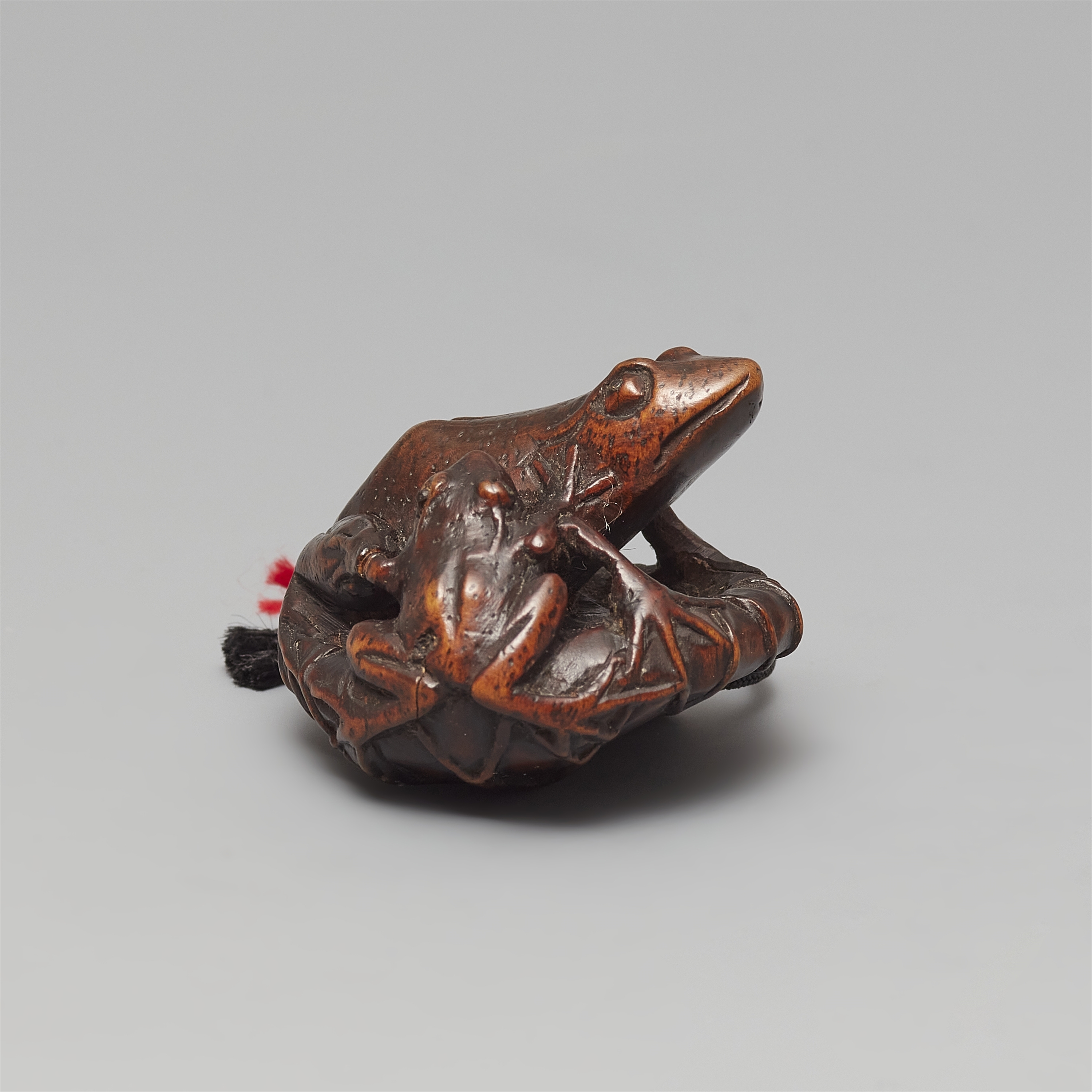 Artwork by Gyokushu, A wood netsuke of two frogs sitting on a lotus leaf, Made of black horn