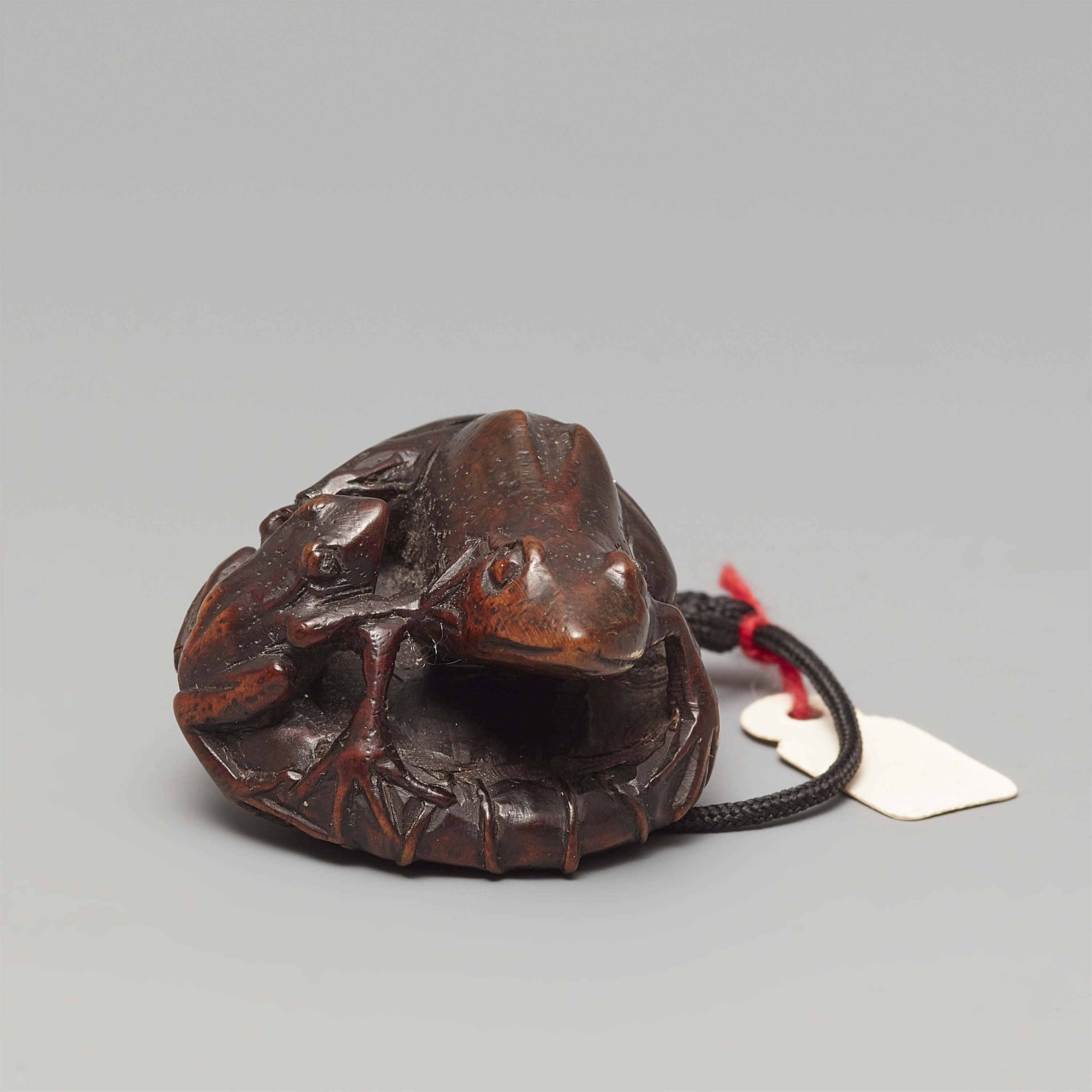 Artwork by Gyokushu, A wood netsuke of two frogs sitting on a lotus leaf, Made of black horn