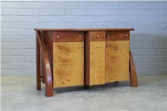 a burr maple and thuya wood inlaid sideboard with a bow front over a breakfront centred with a drawer and a cupboard flanked with cupboards enclosing two shelves with turned ball handles the sides with accentuated shaped supports - Andrew Varah