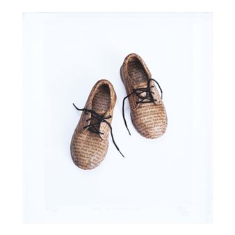A pair of miniature shoes made from printed paper, resting on a stark white surface.