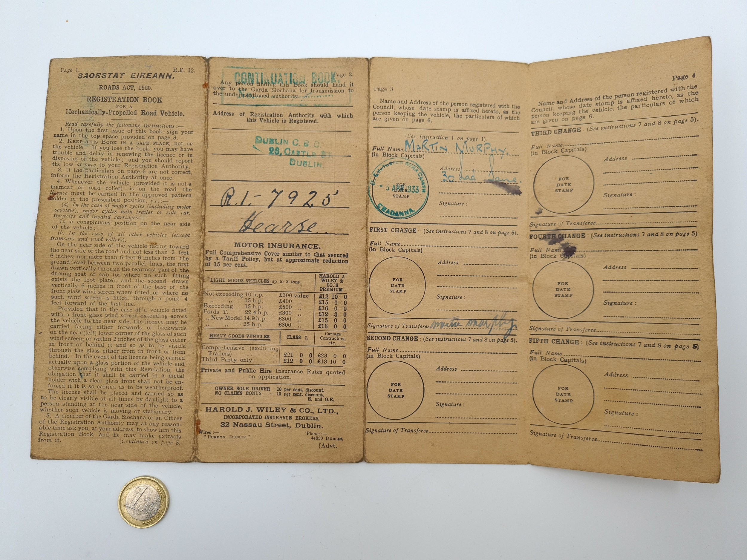 A vintage motor insurance receipt card with a gold coin in the foreground.