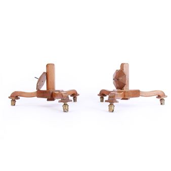 A pair of wooden easel stands with brass feet against a stark white background.