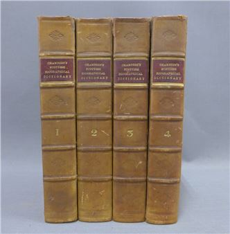 A set of four vintage leather-bound books standing side by side.