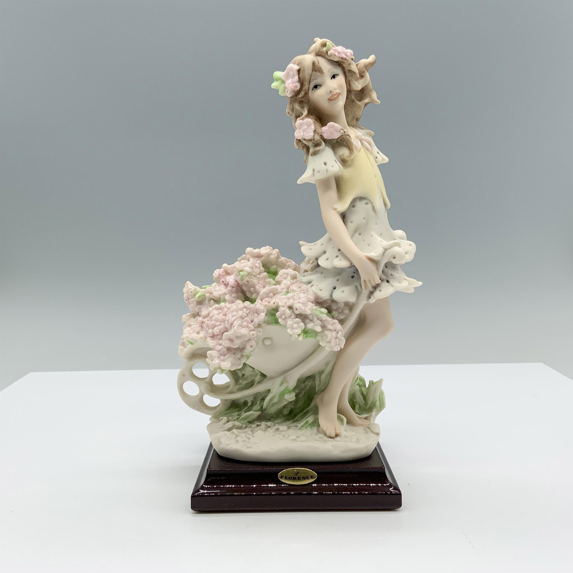 Artwork by Giuseppe Armani, Fine crafted resin with white matte finish captures a young girl carrying a cart full of flowers, Made of resin with white matte