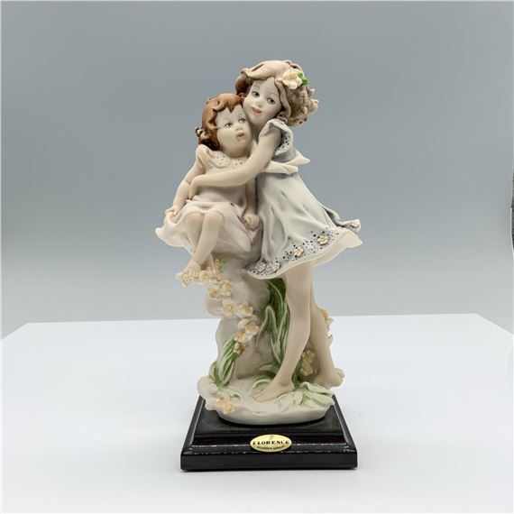 Fine crafted resin with white matte finish captures a young boy giving an apple to a young girl consoling a baby girl