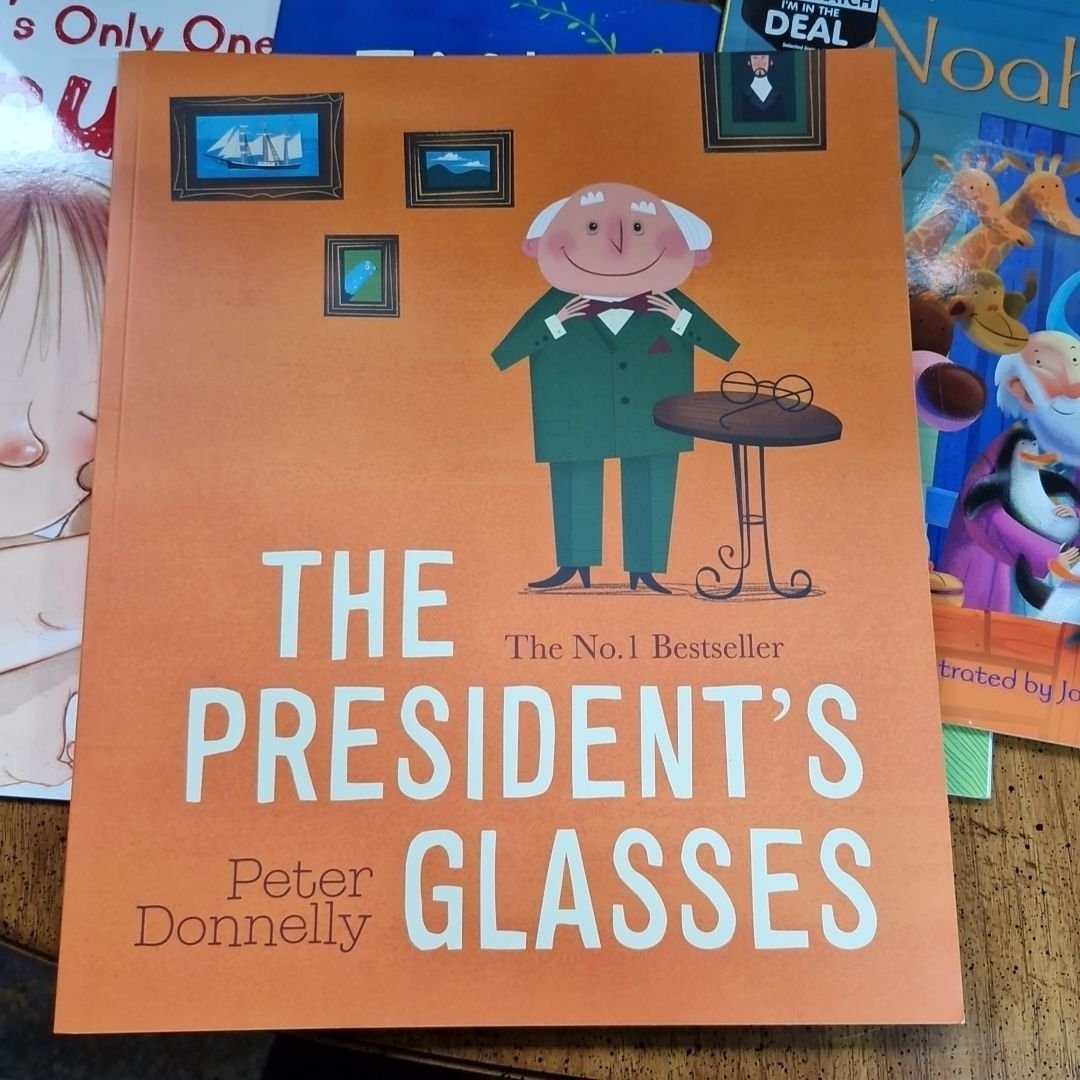 Artwork by Peter Donnelly, Collection of books including titles like "The President's es" by Peter Donnelly, and "Charlie and the Chocolate Factory" activity book, Made of Glass
