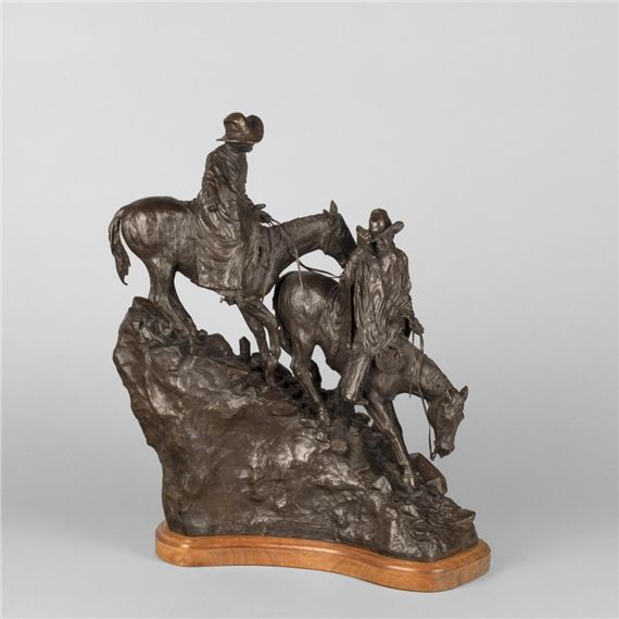 A bronze sculpture of two figures on horseback traversing a rugged rocky terrain.
