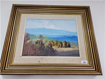 A framed landscape painting depicting a sunlit valley with distant mountains and scattered trees.