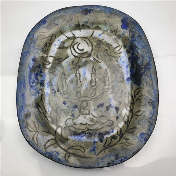 A ceramic bowl with a sun and candle motif, featuring blue glaze accents.