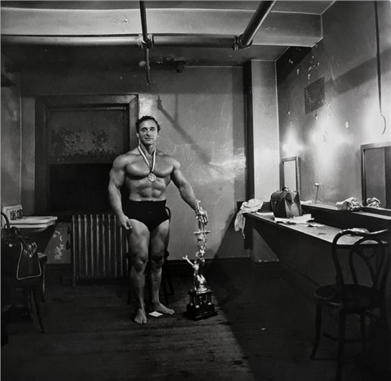 MUSCLE MAN IN HIS DRESSING ROOM WITH TROPHY by Diane Arbus, March 14
