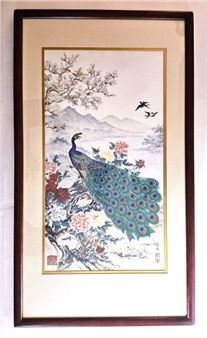 A framed traditional ink painting of a peacock amidst blossoming trees and distant mountains.