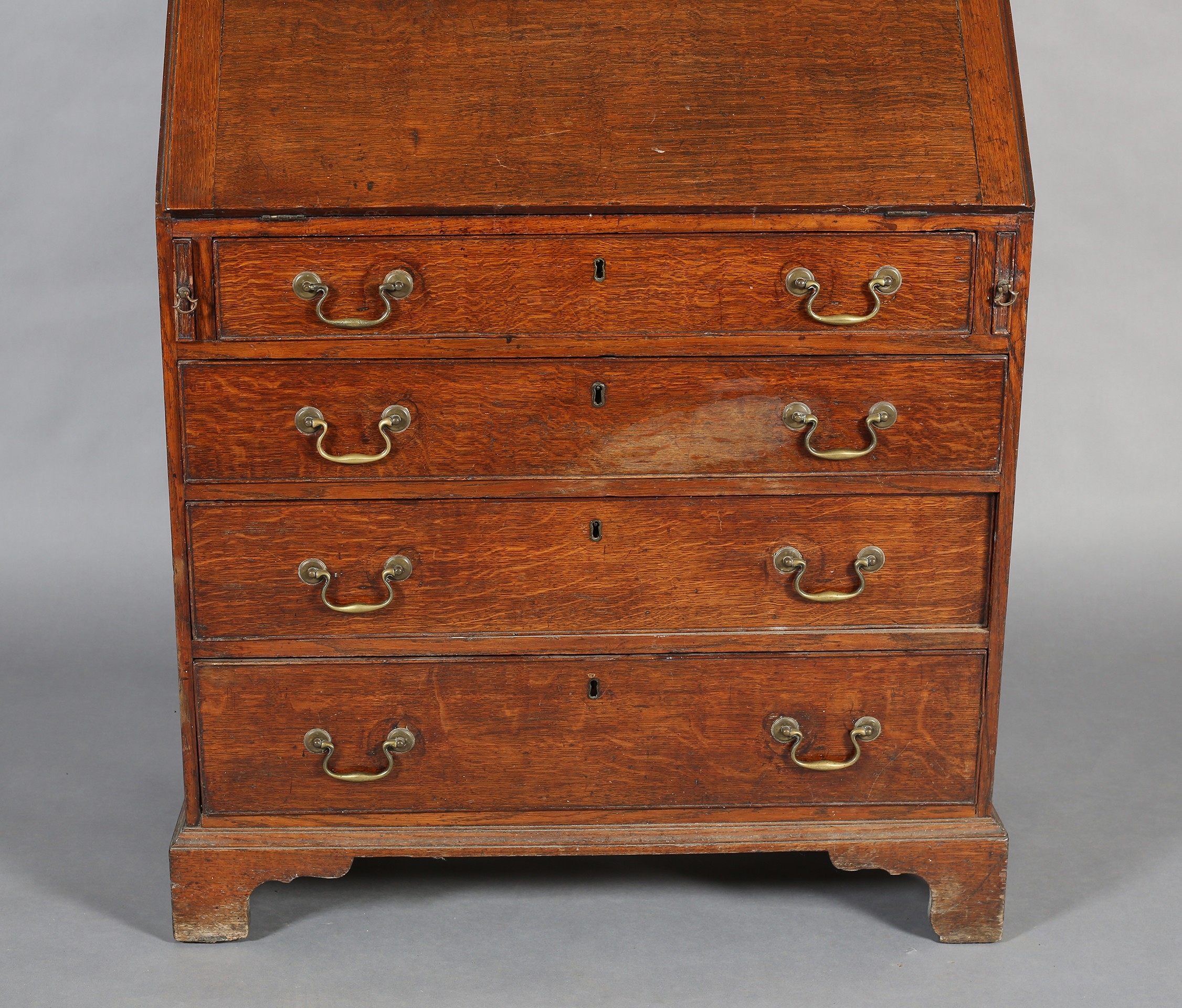 Front | AN EARLYTH CENTURY OAK BUREAU-BOOKCASE, having a break arch ...