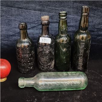 A collection of vintage green glass bottles displayed on a dark surface.