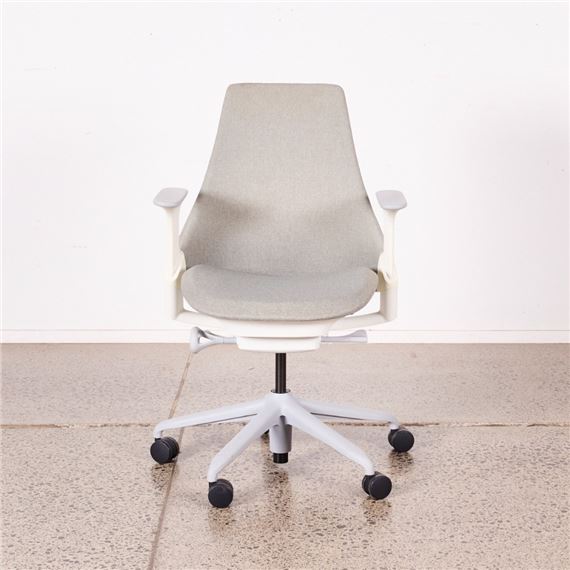 A white office chair sitting on top of a cement floor.