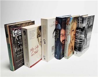 A row of six hardcover books arranged diagonally on a plain surface.