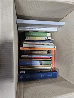 A vertical stack of hardcover books rests inside a textured cardboard box.