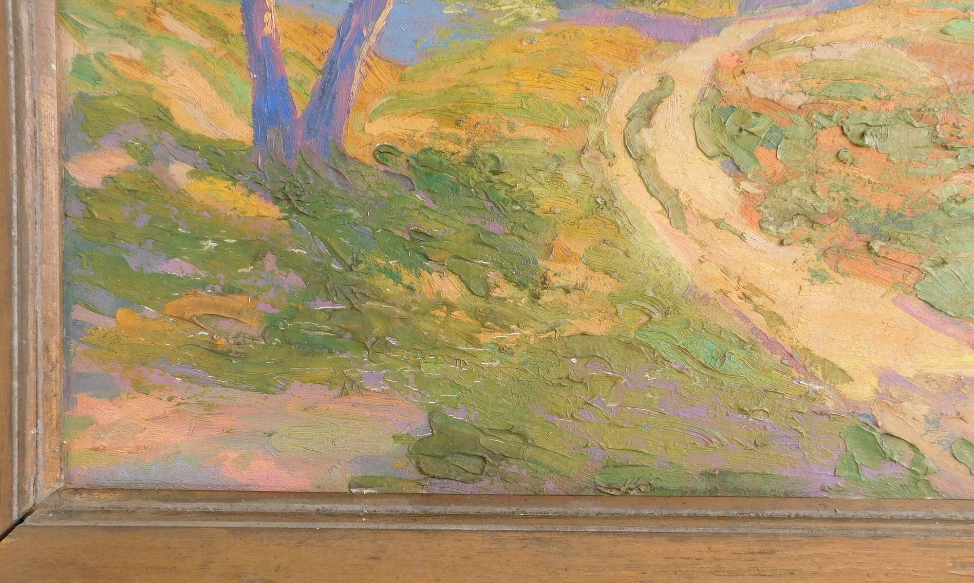 A framed landscape painting of a sunlit path winding through green trees.