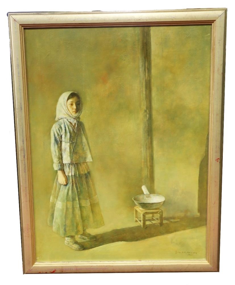 A quiet portrait of a young girl in traditional dress standing beside a simple stool with a bowl on it.