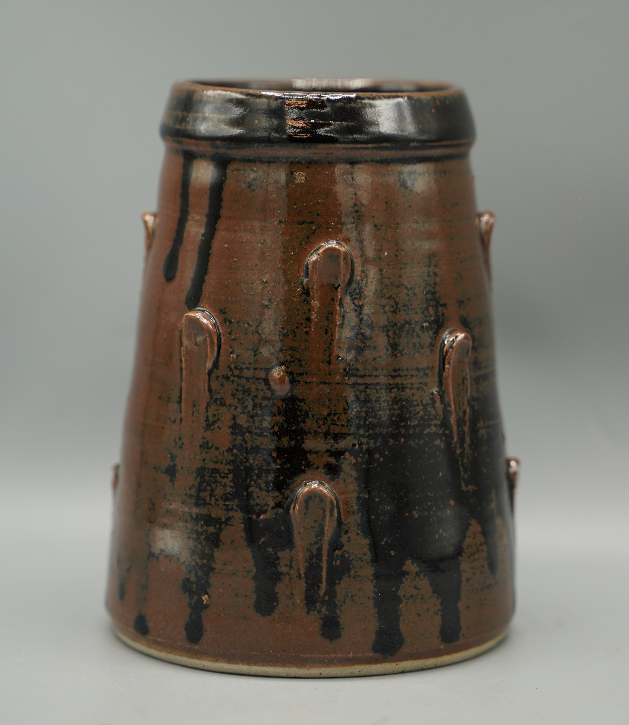 Artwork by Jeremy Leach, Jeremy Leach tapered cylindrical vase, with applied studs in a, Made of brown glaze