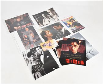 A scattered collection of signed black-and-white and color photographs on a plain white surface.