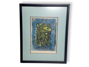 A framed abstract print featuring a stylized face in green and black against a textured blue background.