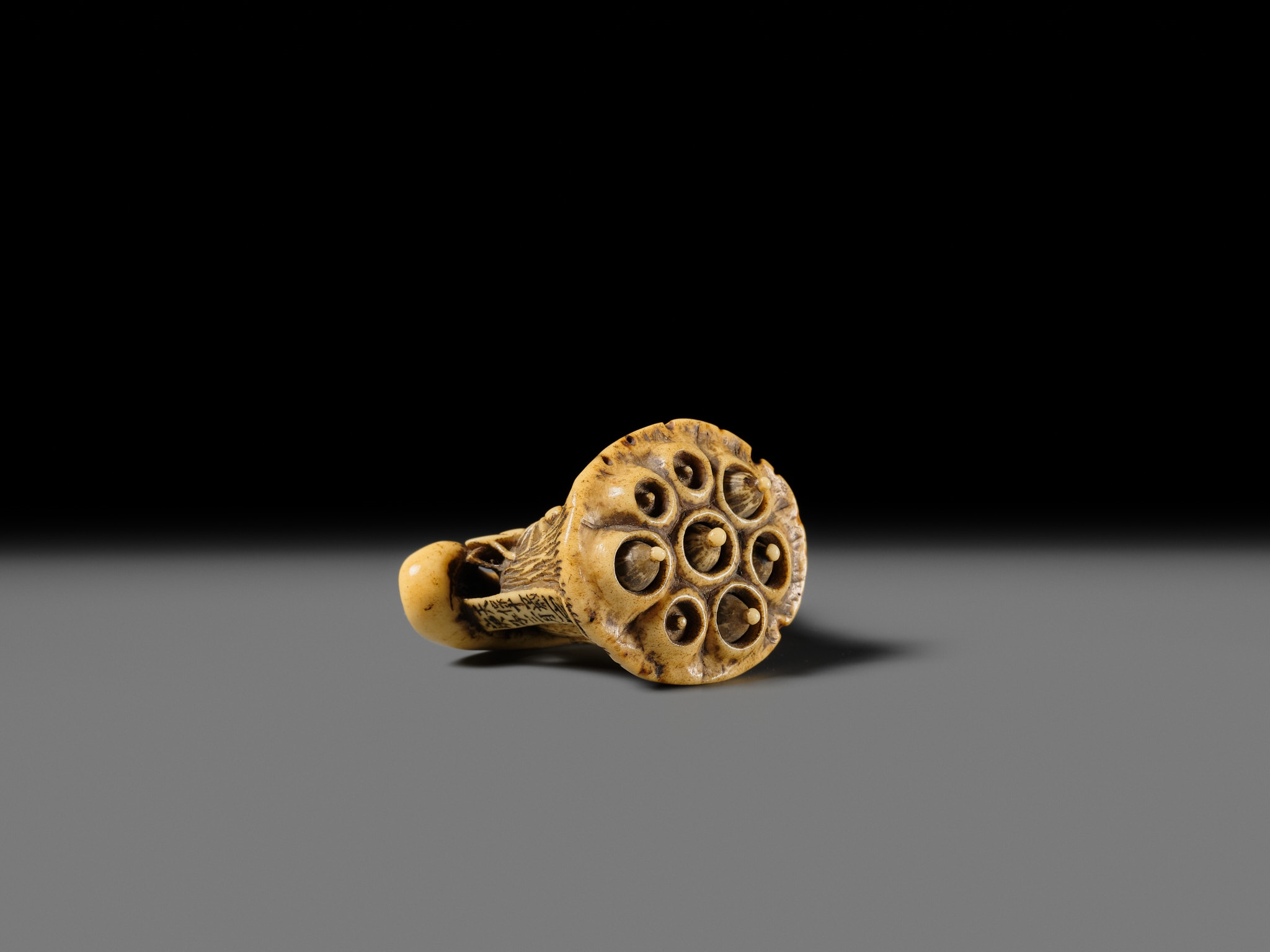 Artwork by Hizen Matsura Ittei, ITTEI: AN ANTLER (TRICK) NETSUKE OF A LOTUS POD WITH THE MAKINO CLAN MON, Made of plaque
